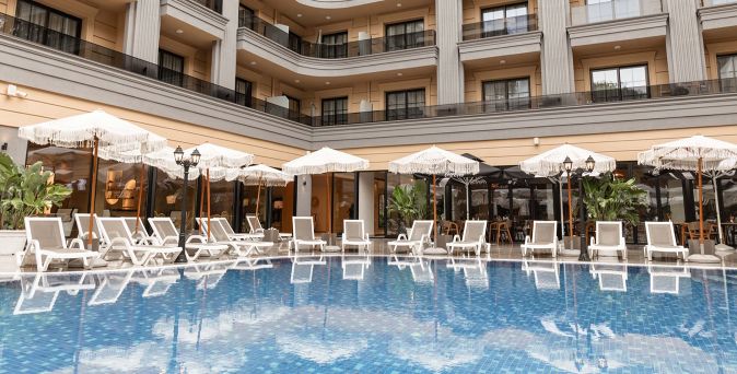 Poolbereich des FAFA Sun Hotels mit weißen Sonnenliegen, dekorativen Sonnenschirmen und mehrstöckigem Hotelgebäude mit Balkonen im Hintergrund