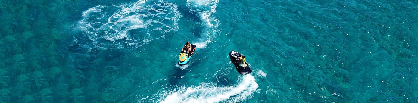 Zwei Personen fahren Jetskis auf klarem, blauem Wasser