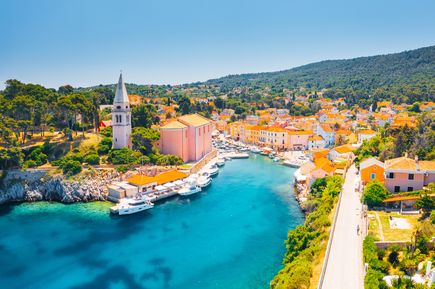 Panoramablick auf Veli Lošinj in der Kvarner Bucht, Kroatien, mit Hafen, pastellfarbenen Häusern, Kirchturm und türkisblauem Meer entlang der Adriaküste