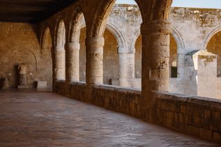 Gewölbter Arkadengang mit steinernen Säulen und Bögen im Archäologischen Museum auf Rhodos.