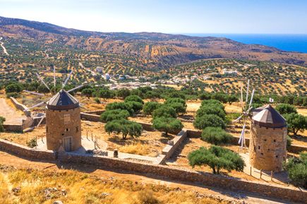 Wasserfall fließt über moosbedeckten Felsen in einen klaren, türkisfarbenen Pool, umgeben von dichtem Grün und Felsen.
