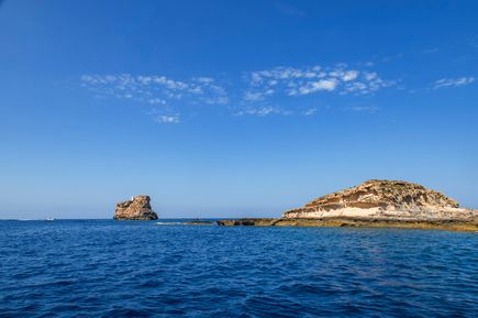 Zwei Felsen im Wasser vor Mallorca, Illa del Toro links, mit klarem blauen Himmel und wenigen Wolken