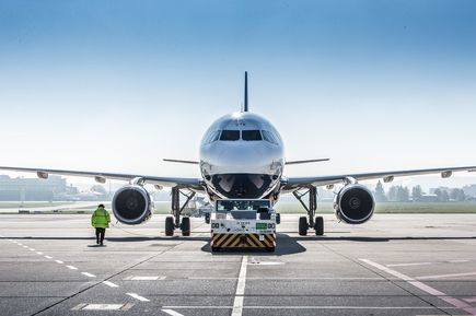 Passagierflugzeug beim Pushback auf dem Vorfeld des Flughafens Stuttgart, Schleppfahrzeug vor dem Jet und Bodenpersonal neben dem Flugzeug