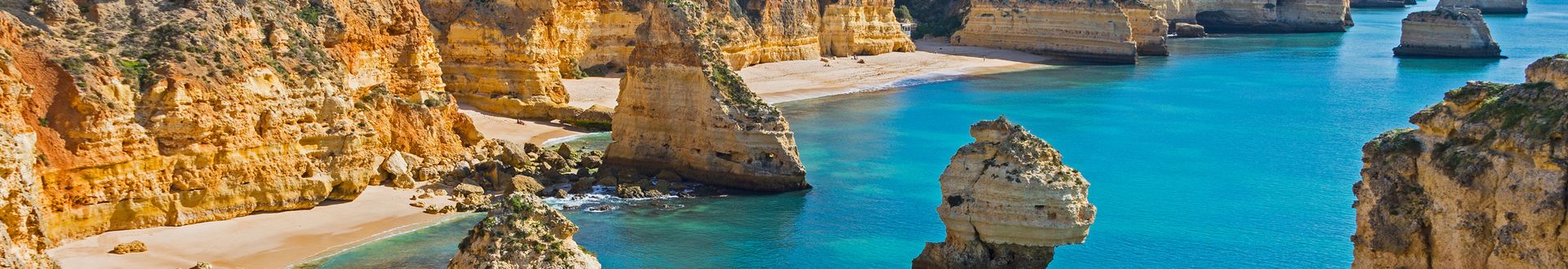 Felsklippen und Sandstrand an der Küste mit türkisfarbenem Wasser in Portugal