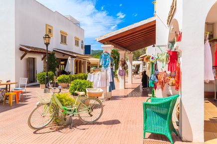Bunte Gassen von San Carlos auf Ibiza mit kleinen Boutiquen, Kleidung und einem Fahrrad im Vordergrund