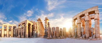 Sonnenuntergang über den Säulen und Statuen des Luxor-Tempels in Ägypten unter blauem Himmel mit Wolken