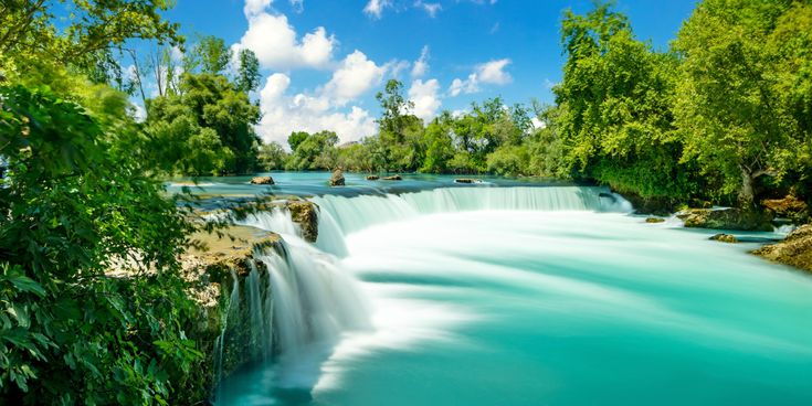 Manavgat-Wasserfälle in der Türkei mit breitem, fließendem Wasser über Felskante, türkisfarbenem Becken und dichter grüner Vegetation