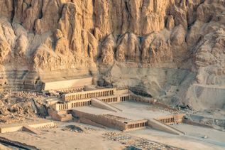 Der Totentempel der Hatschepsut eingebettet in eine felsige Wüstenlandschaft in Ägypten