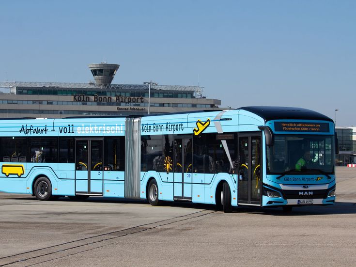 Elektrischer Flughafenbus auf dem Vorfeld des Flughafens Köln/Bonn vor dem Terminalgebäude mit sichtbarem Schriftzug „Köln Bonn Airport Konrad Adenauer“