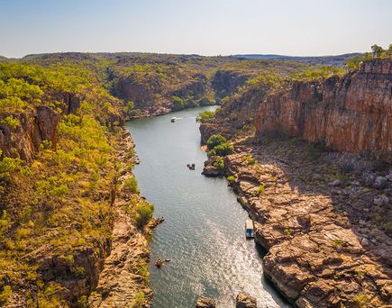 Fluss fließt zwischen bewaldeten und felsigen Steilufern unter klarem Himmel.