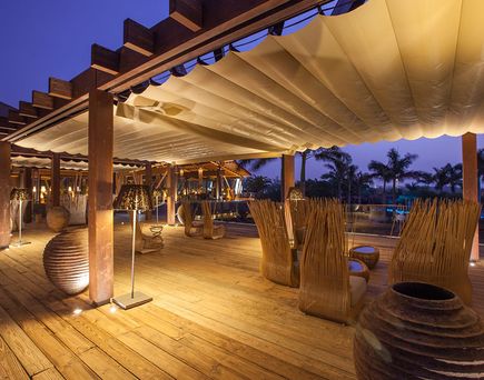 Stimmungsvoll beleuchteter Outdoor‑Loungebereich aus Holz mit gemütlichen Sitzbereichen im Lopesan Baobab Resort