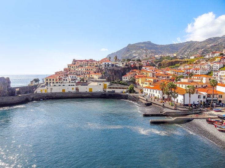 Blick auf die Küstenstadt Funchal auf Madeira mit Hafenbucht, dicht bebauten Berghängen und Häusern mit roten Ziegeldächern.
