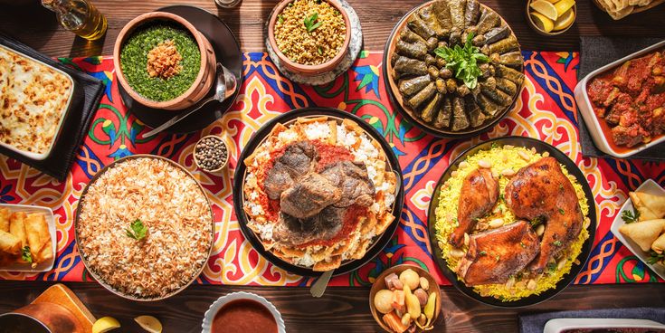 Bunte Tafel mit verschiedenen arabischen Gerichten wie gefüllte Weinblätter, Reis, Huhn, Eintöpfen und Beilagen auf dekorativer Tischdecke