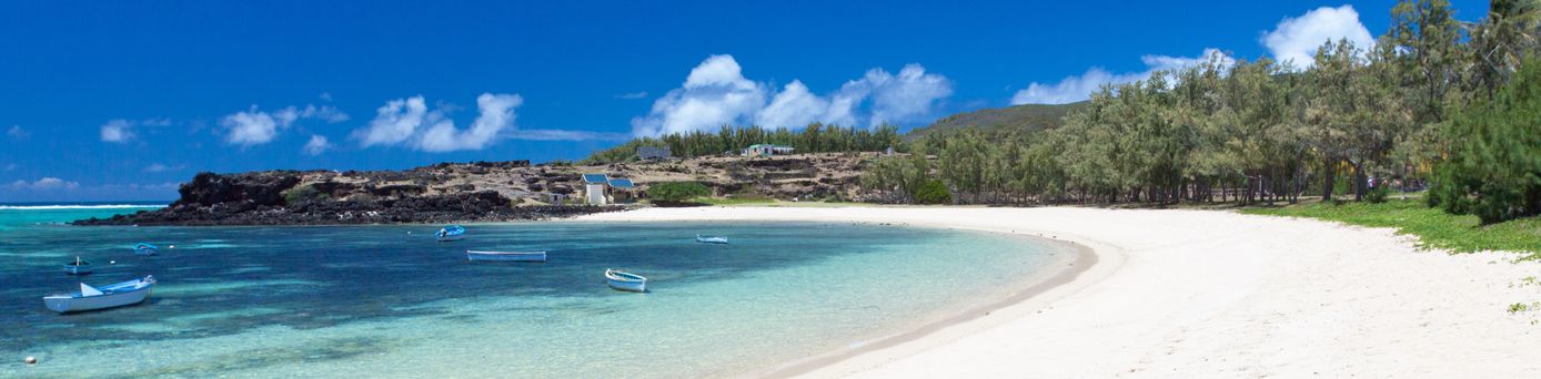 Sandstrand mit klarem türkisfarbenem Wasser, zwei kleinen Booten und bewaldetem Ufer bei Rodrigues Island