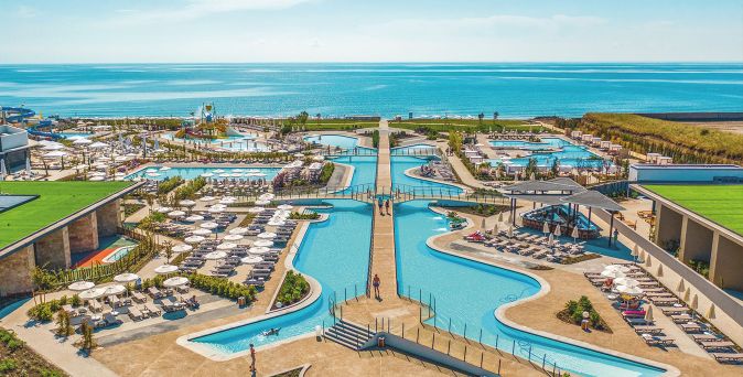 Weitläufige Resortanlage mit mehreren Pools, Liegen und einem direkten Blick auf das Meer.