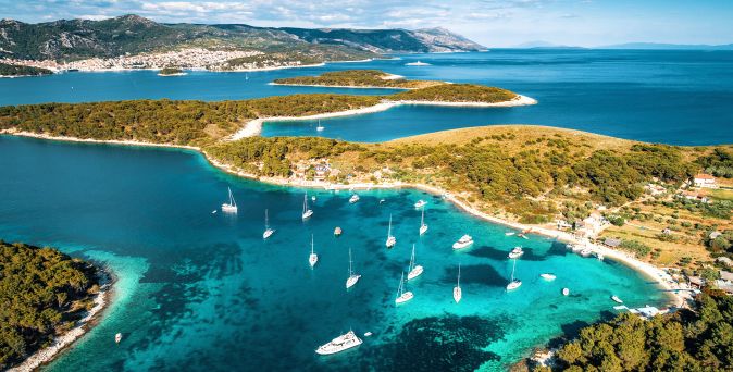 Panorama der Pakleni-Inseln vor Hvar in Kroatien mit bewaldeten Inseln, türkisfarbenen Buchten und zahlreichen Segelbooten im Adriatischen Meer