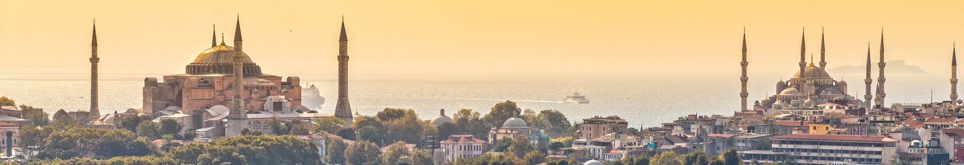 Panoramablick über Istanbul mit Hagia Sophia und Blauer Moschee im warmen Abendlicht, davor die historischen Stadtviertel und dahinter das glitzernde Wasser des Bosporus