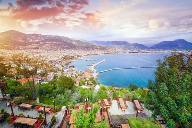 Panorama von Alanya mit Blick auf den Hafen, den roten Turm und die weitläufige Stadtlandschaft vor der Bergkulisse