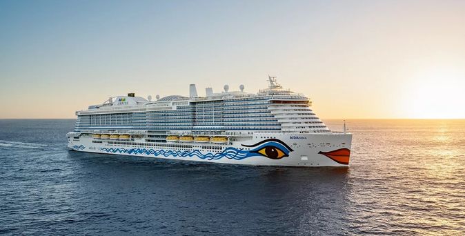 Kreuzfahrtschiff AIDA mit markantem Augen- und Lippenmotiv am Bug fährt bei Sonnenuntergang auf dem Meer