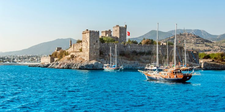 Burg von Bodrum an der türkischen Ägäisküste mit Segelbooten im Vordergrund und tiefblauem Meer bei klarem Himmel