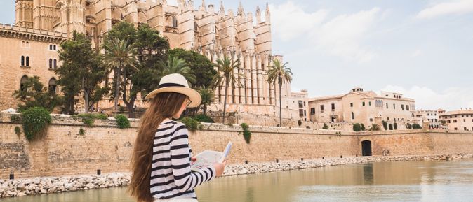 Reisende mit Sonnenhut betrachtet eine Karte vor der gotischen Kathedrale La Seu in Palma de Mallorca