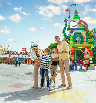 Familie mit zwei Kindern vor buntem LEGO-Schloss und LEGOLAND Dubai Eingang bei sonnigem Himmel.
