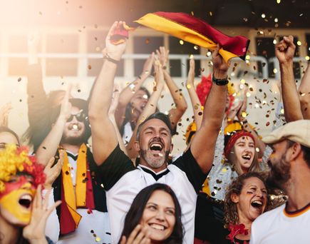 Gruppe jubelnder Deutschland-Fans mit erhobenen Armen und Konfetti in der Luft