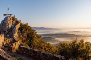Kloster auf bewaldetem Hügel mit Blick auf das offene Meer unter blauem Himmel