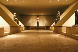 Innenraum des Luxor-Museums in Ägypten mit antiken ägyptischen Statuen, symmetrisch angeordnet in einem Ausstellungsraum, warme Beleuchtung und Steinboden