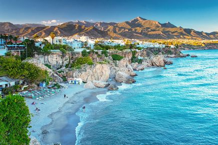 Aussicht auf die Küste von Nerja mit Felsen, Stränden und weißen Häusern vor den Bergen Andalusiens