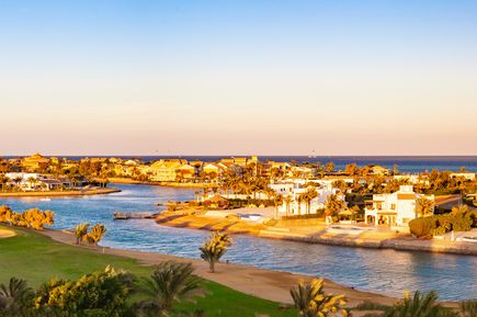 Blick auf El Gouna mit Wasserkanälen, weißen Gebäuden, Palmen und Golfplatz am Meer bei Sonnenuntergang