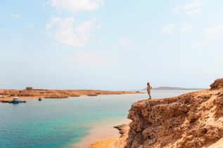 Frau steht auf einer Klippe und blickt auf das blaue Meer im Ras-Mohammed-Nationalpark in Ägypten