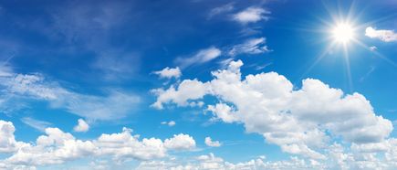 Strahlend blauer Himmel mit weißen Wolken und leuchtender Sonne