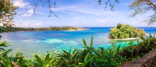 Blick auf die San San Bay in Jamaika mit türkisfarbenem Wasser, kleinen Inseln und tropischer Vegetation entlang der Küste