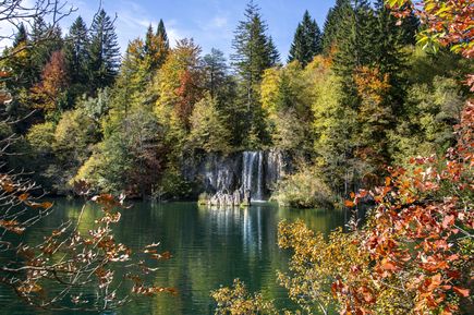 Wasserfall im Nationalpark Plitvicer Seen in Kroatien im Herbst, umgeben von bunten Laubbäumen und ruhigem See