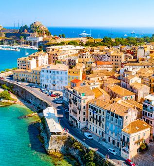 Luftaufnahme der Küstenstadt mit dicht bebauten Häusern und einer Festung am Meer