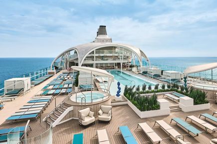Blick auf das Sonnendeck der „Mein Schiff Relax“ mit Liegestühlen, Poolbereich, Whirlpool und moderner, heller Architektur vor dem Hintergrund des offenen Meeres