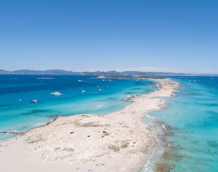 Luftaufnahme des Playa de ses Illetes auf Formentera mit feinem weißen Sand, türkisblauem Meer und Yachten im Wasser