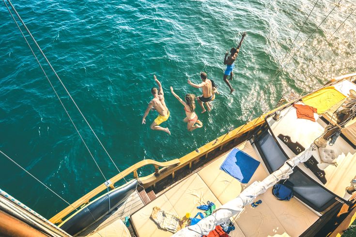 Mehrere Personen springen vom Katamaran ins Meer