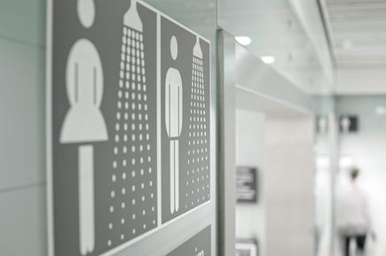 Beschilderung für Duschen am Flughafen München mit Piktogrammen für Personen und Duschsymbol, moderne Innenraumansicht eines Sanitärbereichs im Terminal