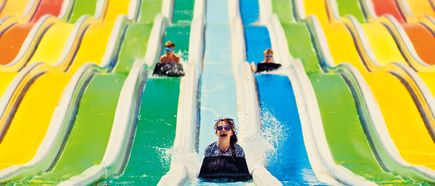 Kinder rutschen auf bunten Wasserrutschen mit Matten in einem Aquapark