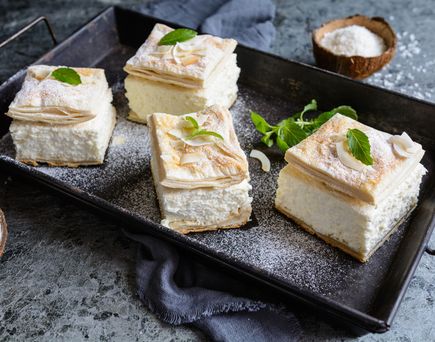 Hausgemachte Cremeschnitten mit knusprigem Blätterteig und Puderzucker auf Tablett