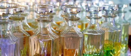 Reihe von transparenten Parfüm-Glasflakons mit verschiedenen farbigen Flüssigkeiten, eng nebeneinander