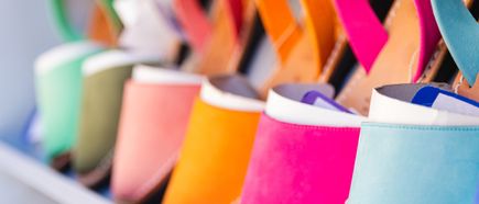 Mehrere bunte Lederschuhe stehen nebeneinander in einer Reihe und präsentieren kräftige Farben wie Pink, Orange und Türkis