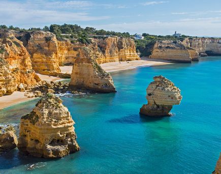 Küste der Algarve mit markanten Felsformationen und klarem blauem Wasser unter bewölktem Himmel