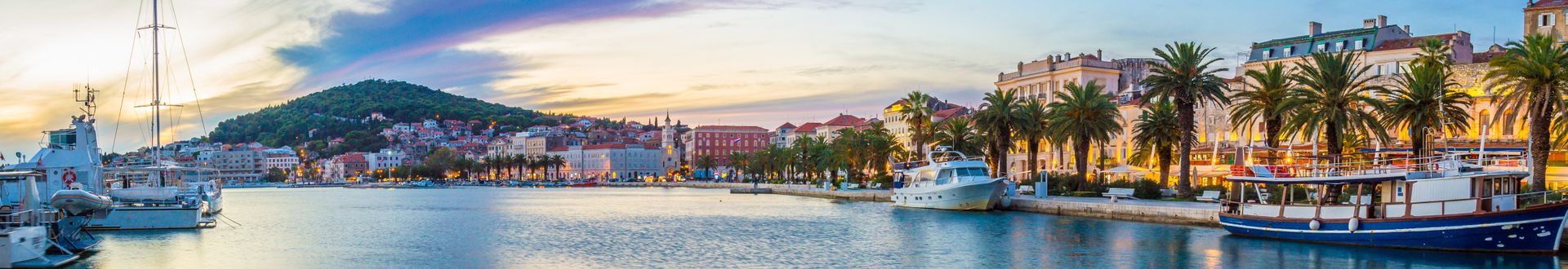 Küste von Split in Mitteldalmatien, Kroatien, bei Sonnenuntergang mit Hafen, Booten und Palmenpromenade