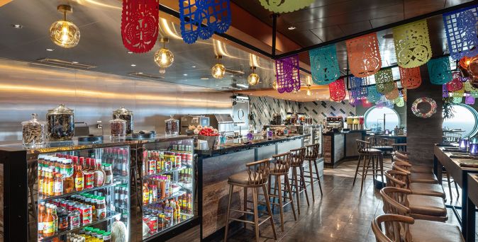 Mexikanisches Restaurant ‚Hola! Tacos & Cantina‘ auf der MSC Euribia mit farbenfrohen Papiergirlanden und moderner Bar
