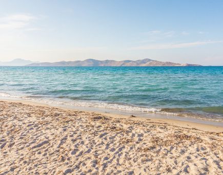 Sandstrand mit leichtem Wellengang und Inseln am Horizont
