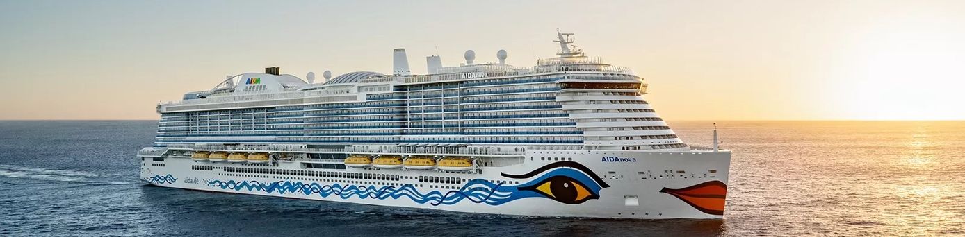 Kreuzfahrtschiff AIDA mit markantem Augen- und Lippenmotiv am Bug fährt bei Sonnenuntergang auf dem Meer