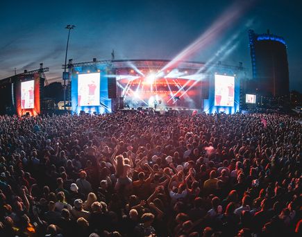 Große Open-Air-Konzertbühne am Abend mit intensiver Lichtshow vor Publikum beim Inselfieber-Festival